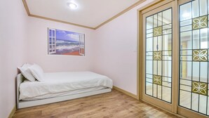 A bedroom with a single bed, a window with a beach view, and a sliding glass door with decorative panels. - Sokcho Dderak Pension (Sokcho)