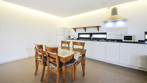 A modern kitchen with white cabinets, a built-in microwave, and a gas stove. - Namhae Liebe Pension (Namhae)