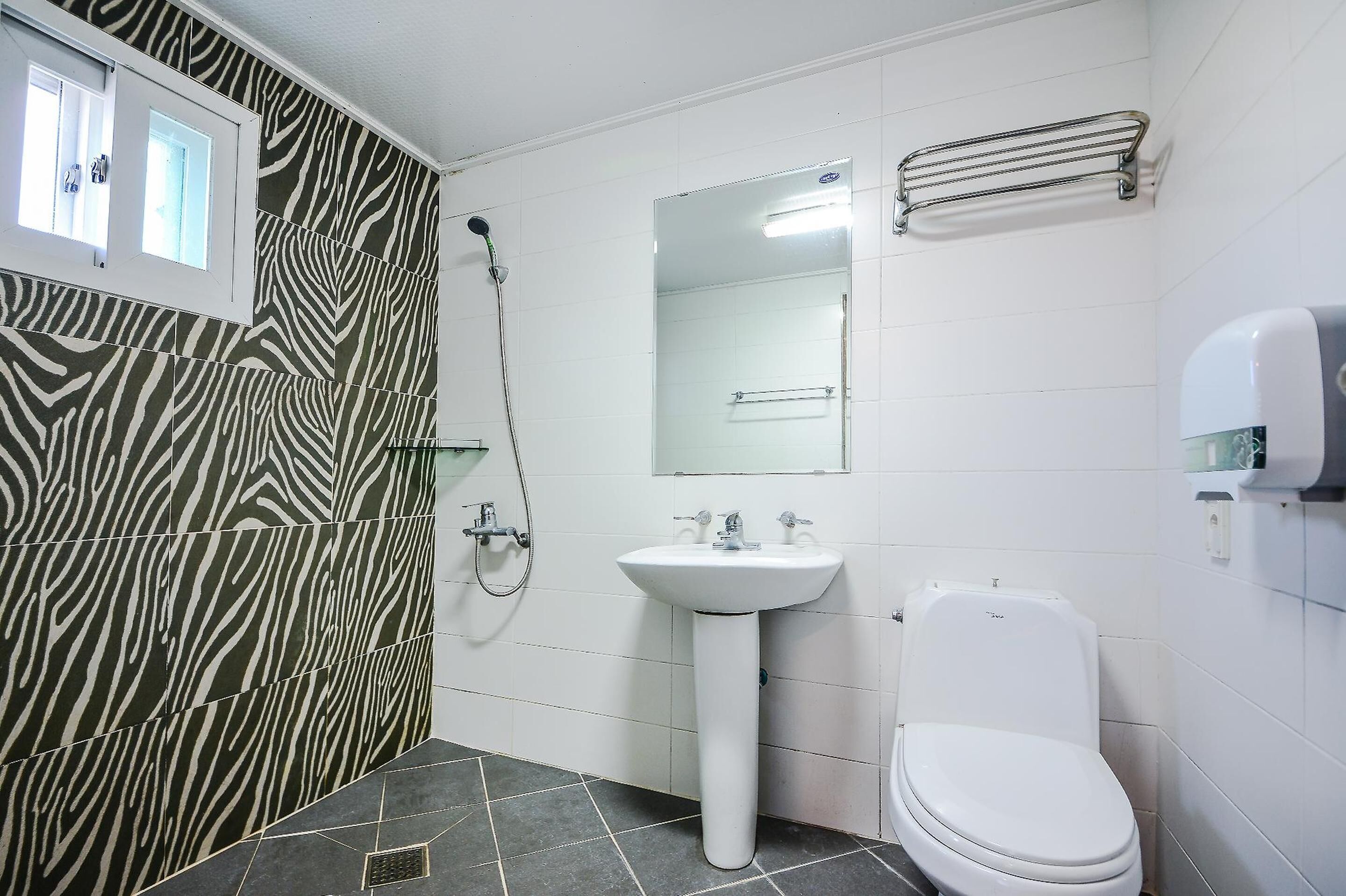 A bathroom with zebra-patterned tiles, a white sink, a toilet, and a shower.