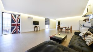 A modern living room with a black leather sofa, a glass coffee table, and a dining area with wooden chairs. - Namhae Liebe Pension (Namhae)