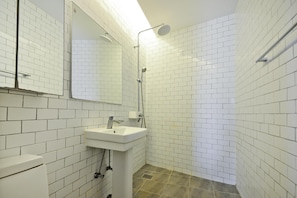 A bathroom with white tiled walls, a sink, a mirror, and a shower.