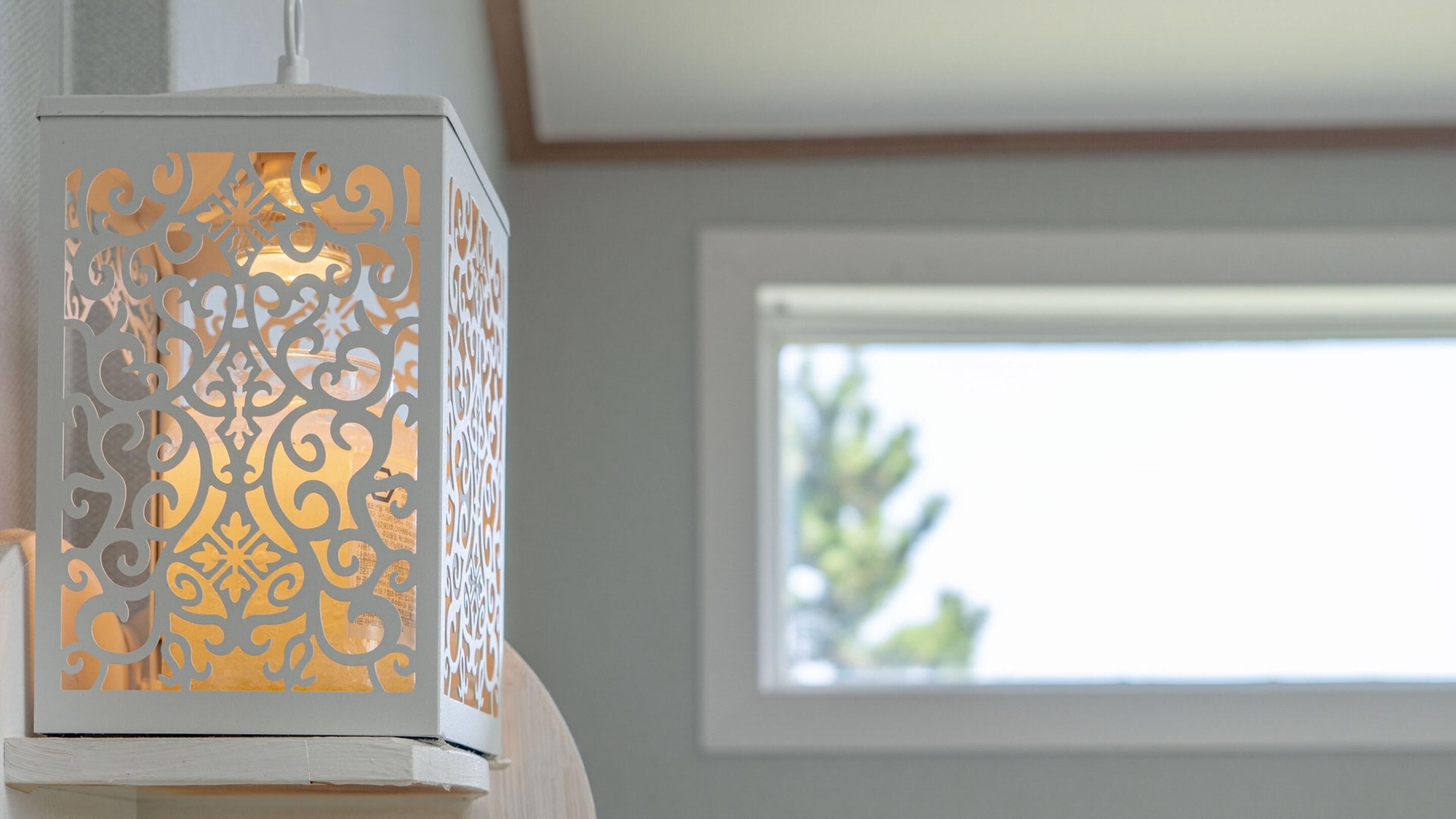 A white decorative lantern with intricate cut-out patterns.