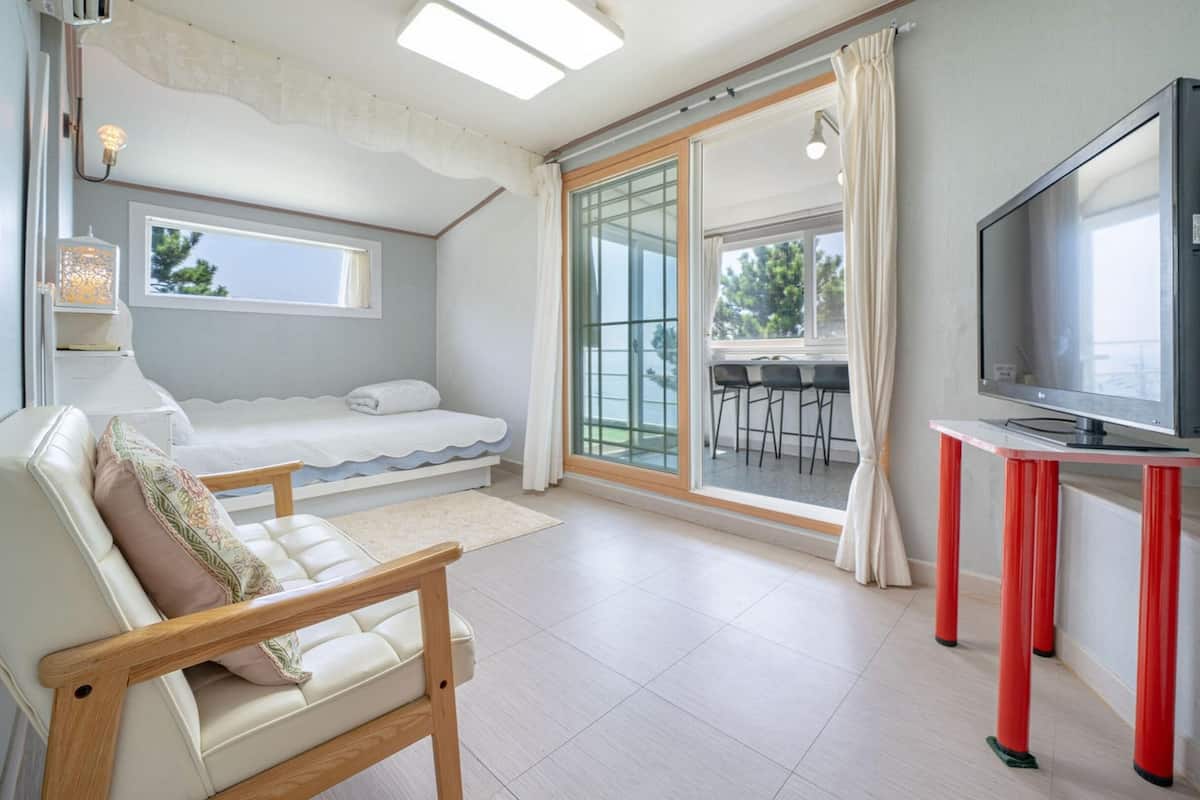 A modern bedroom with a bed, a TV, and a balcony with a view.