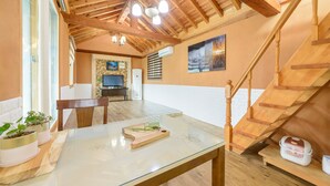 A cozy room with a glass table, wooden staircase, and a TV mounted on the wall. - Gapyeong Ebenzer Pension (Gapyeong)