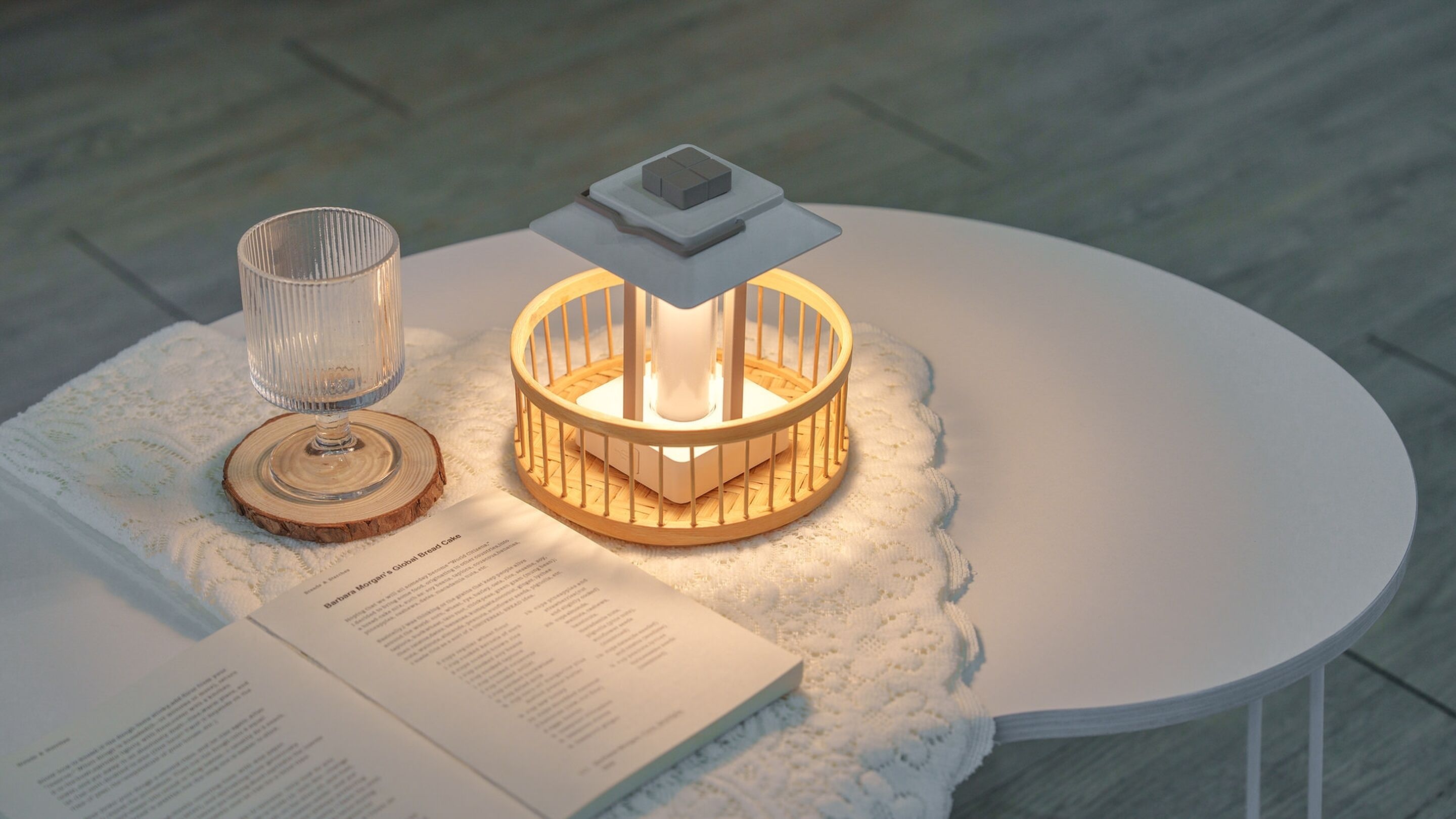 Une table avec une bougie blanche, un sous-verre en bois et un petit livret.