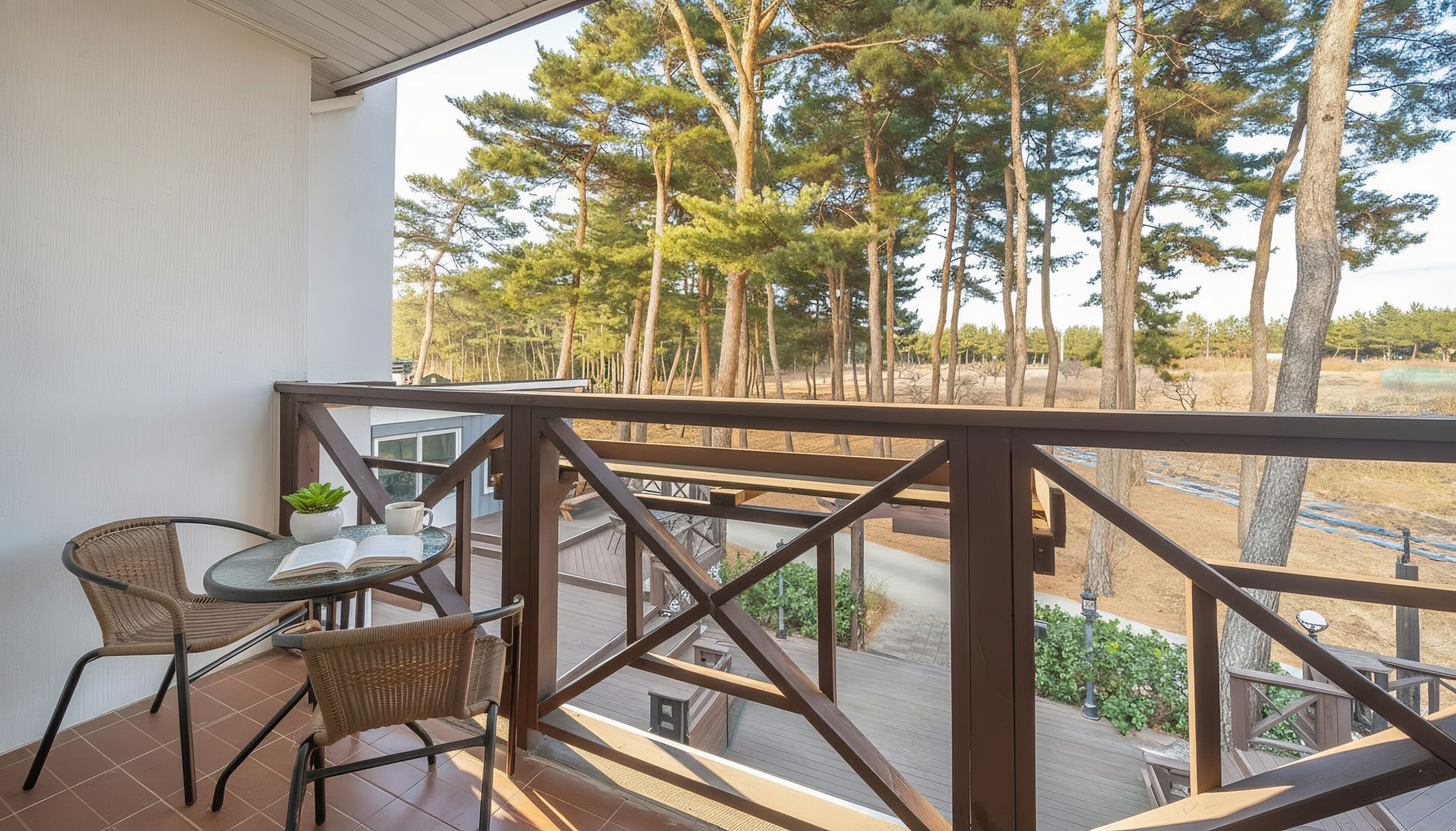 A balcony with wicker chairs, a small table, and a potted plant.