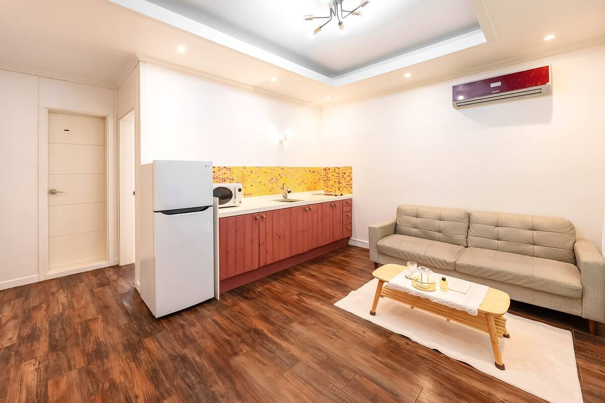 A compact living space with a kitchenette, a sofa, and a dining table.
