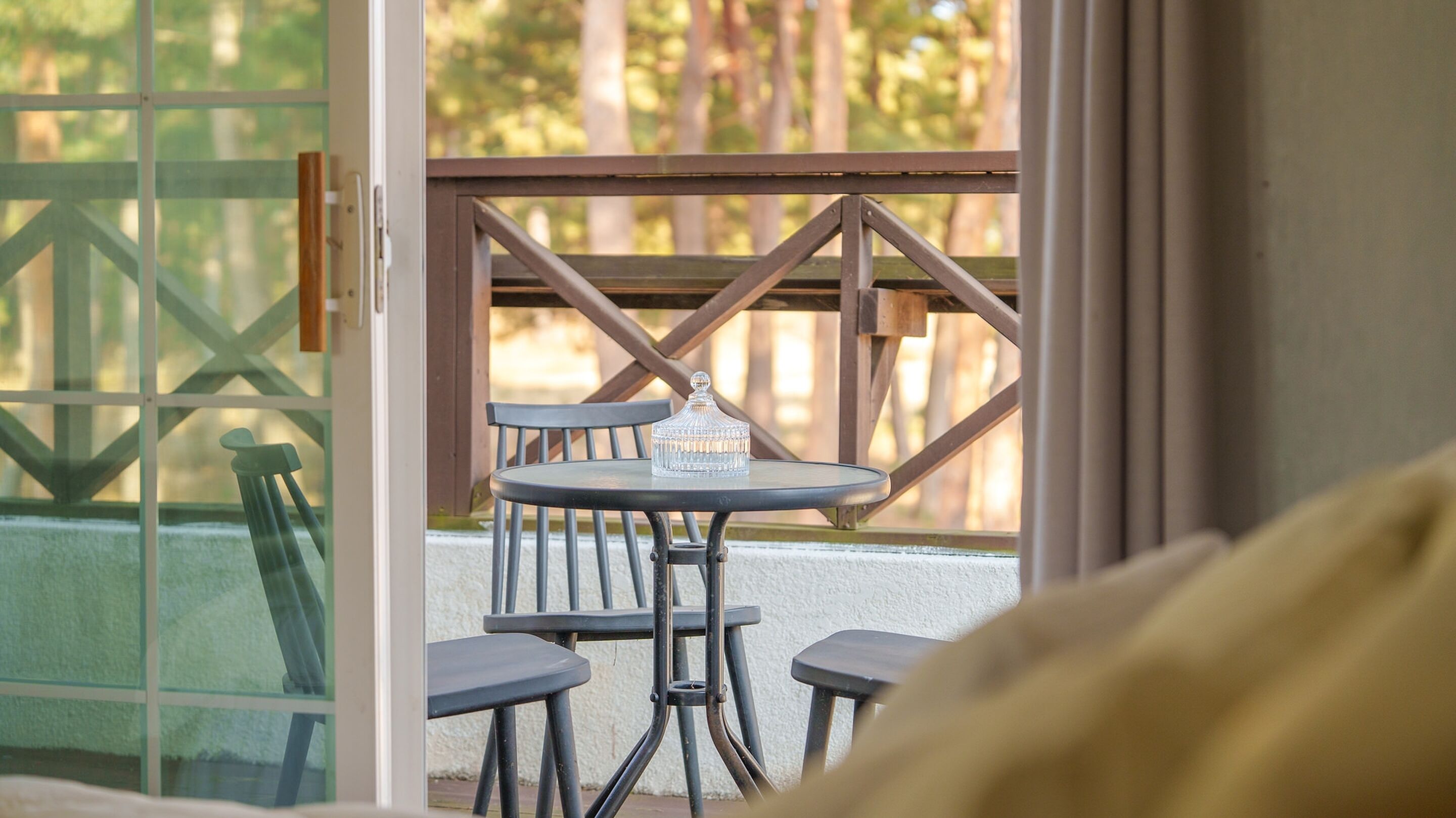 A view of a room with a glass door leading to an outdoor area with a table and chairs.