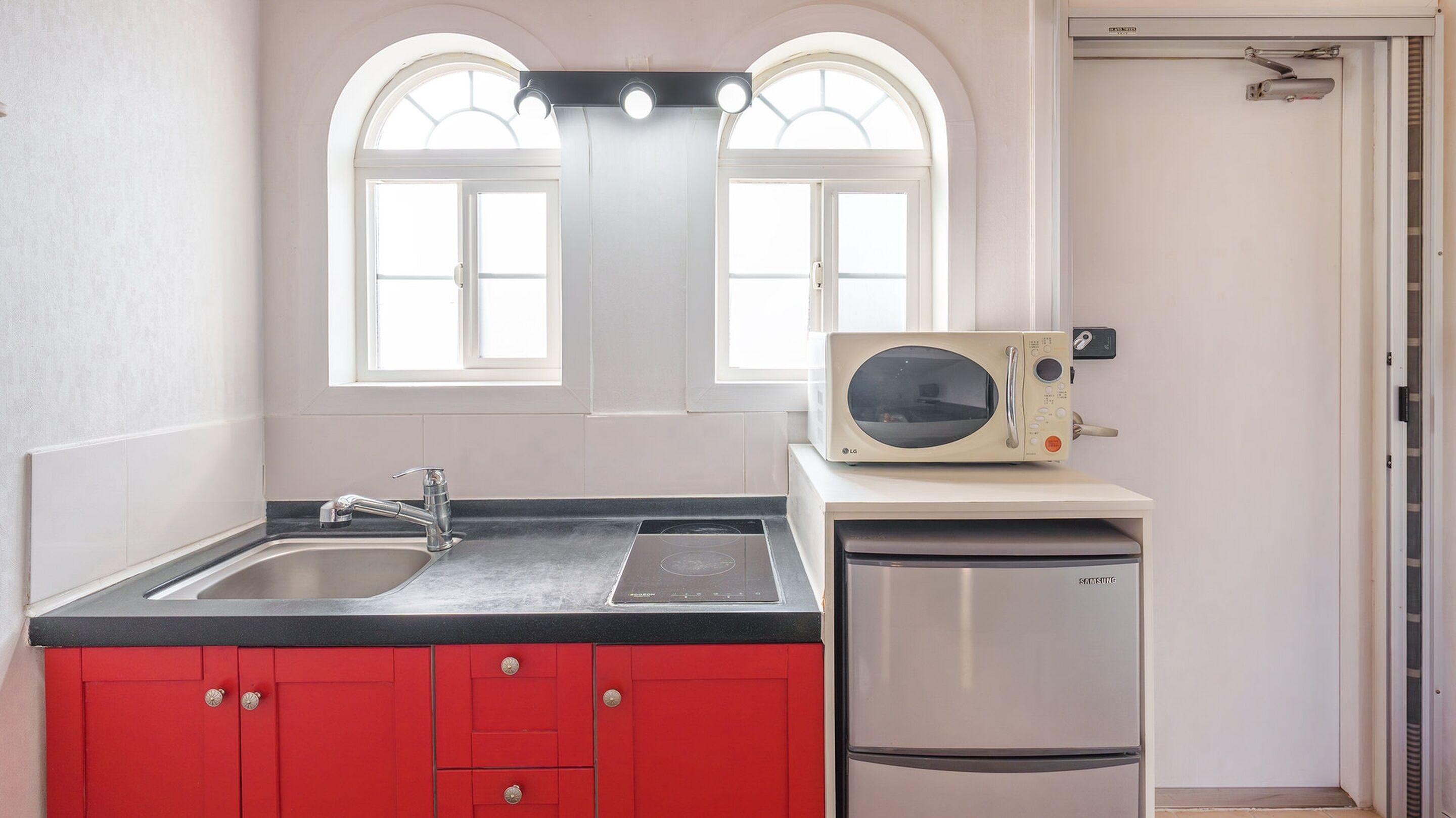 Een keuken met een spoelbak, een magnetron en een koelkast.