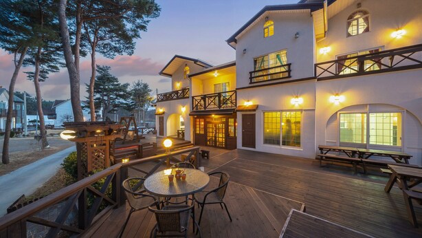 A multi-story building with outdoor seating and a wooden deck. - The Gangneung Foret Pension (Gangneung)