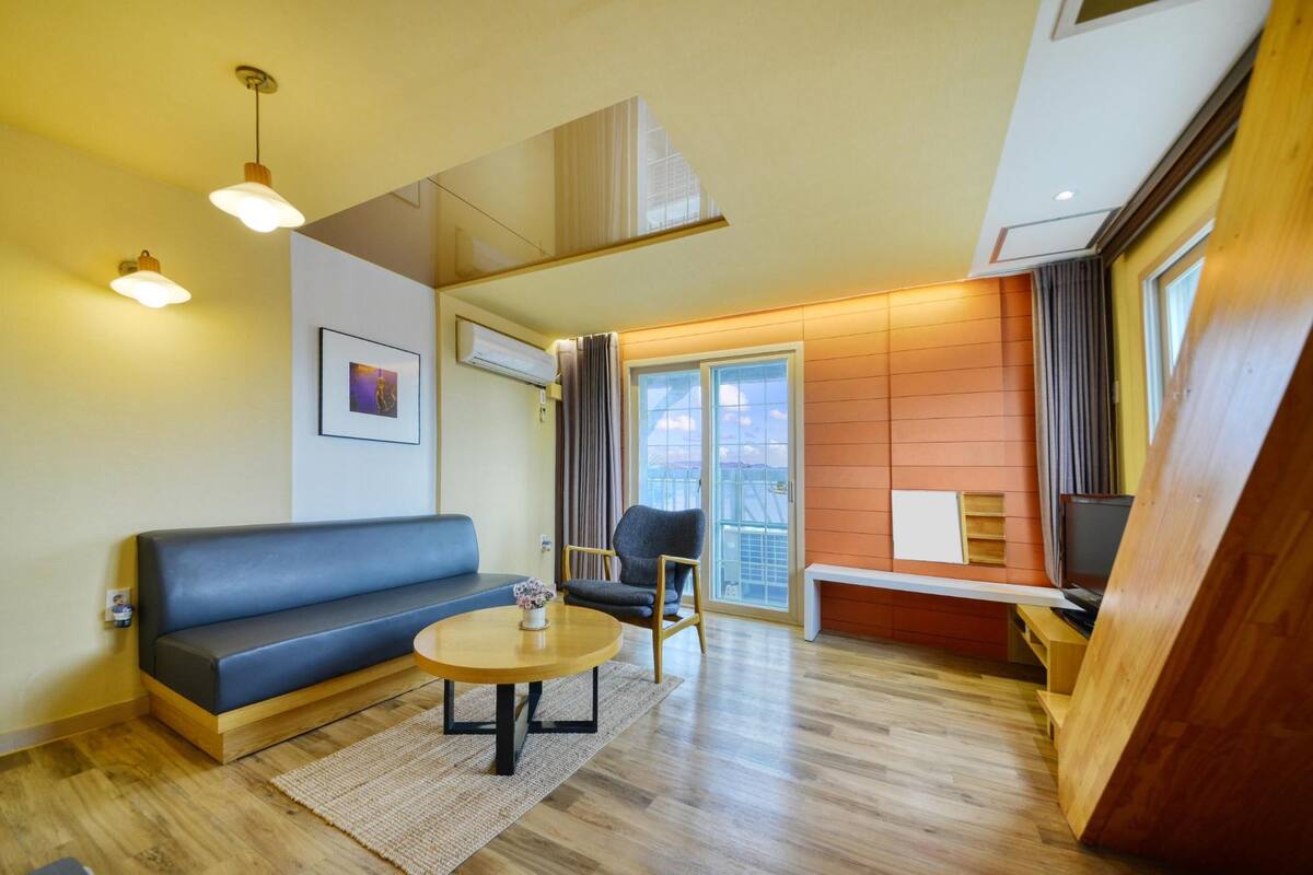Una sala de estar moderna con un sofá, una mesa de centro redonda y un mueble para televisión.