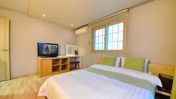 Un dormitorio con cama, televisión, escritorio y ventana.