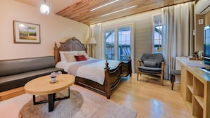 Un dormitorio con techo de madera, una cama, un sofá, un escritorio y un televisor.