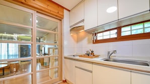 Una cocina moderna con armarios de madera, un lavamanos de acero inoxidable y un ventanal con vistas a un comedor.