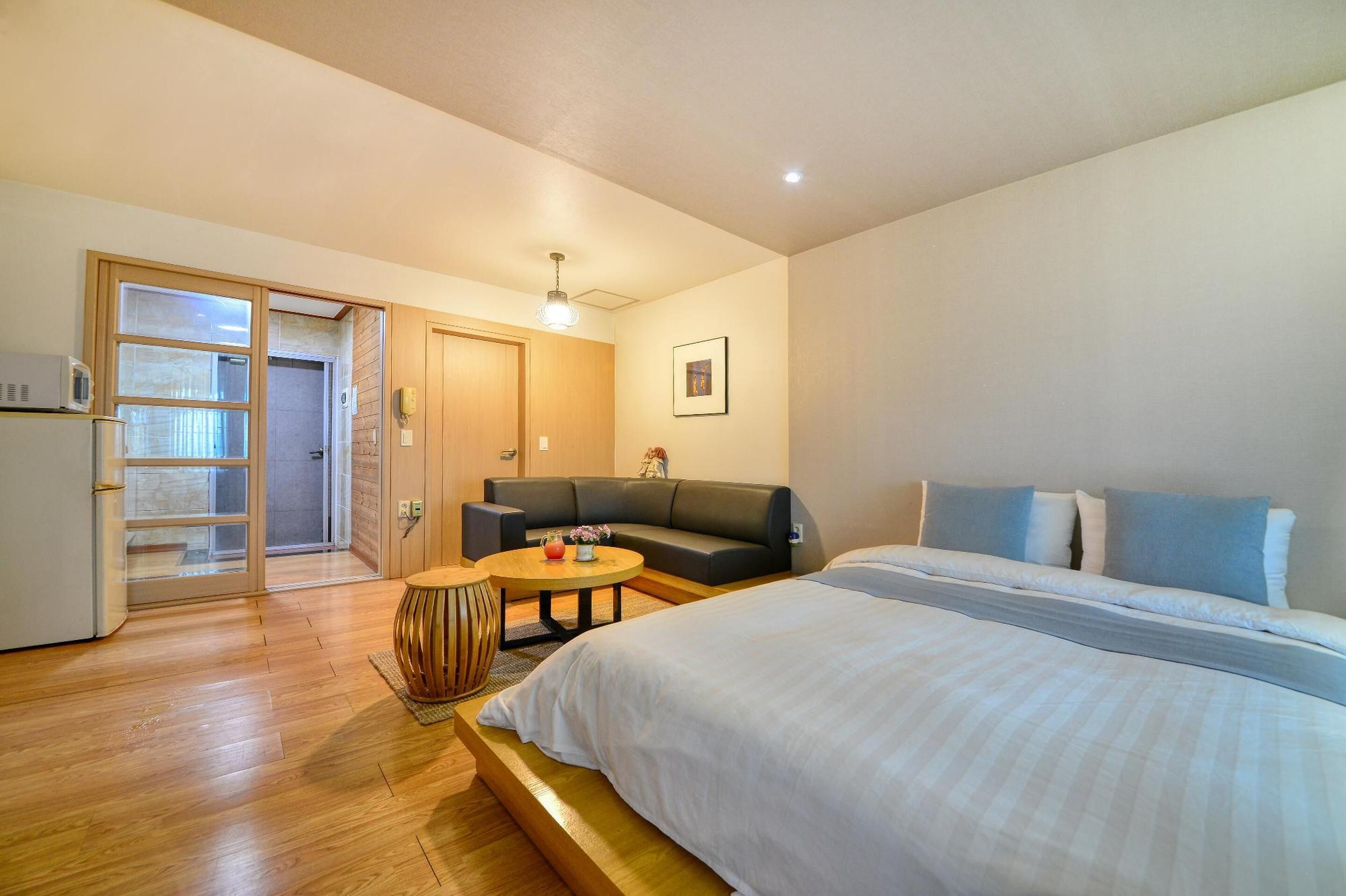 Una habitación de hotel con una cama, un sofá, una mesita redonda y un microondas.