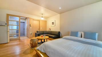 Una habitación de hotel con una cama, un sofá, una mesita redonda y un microondas.