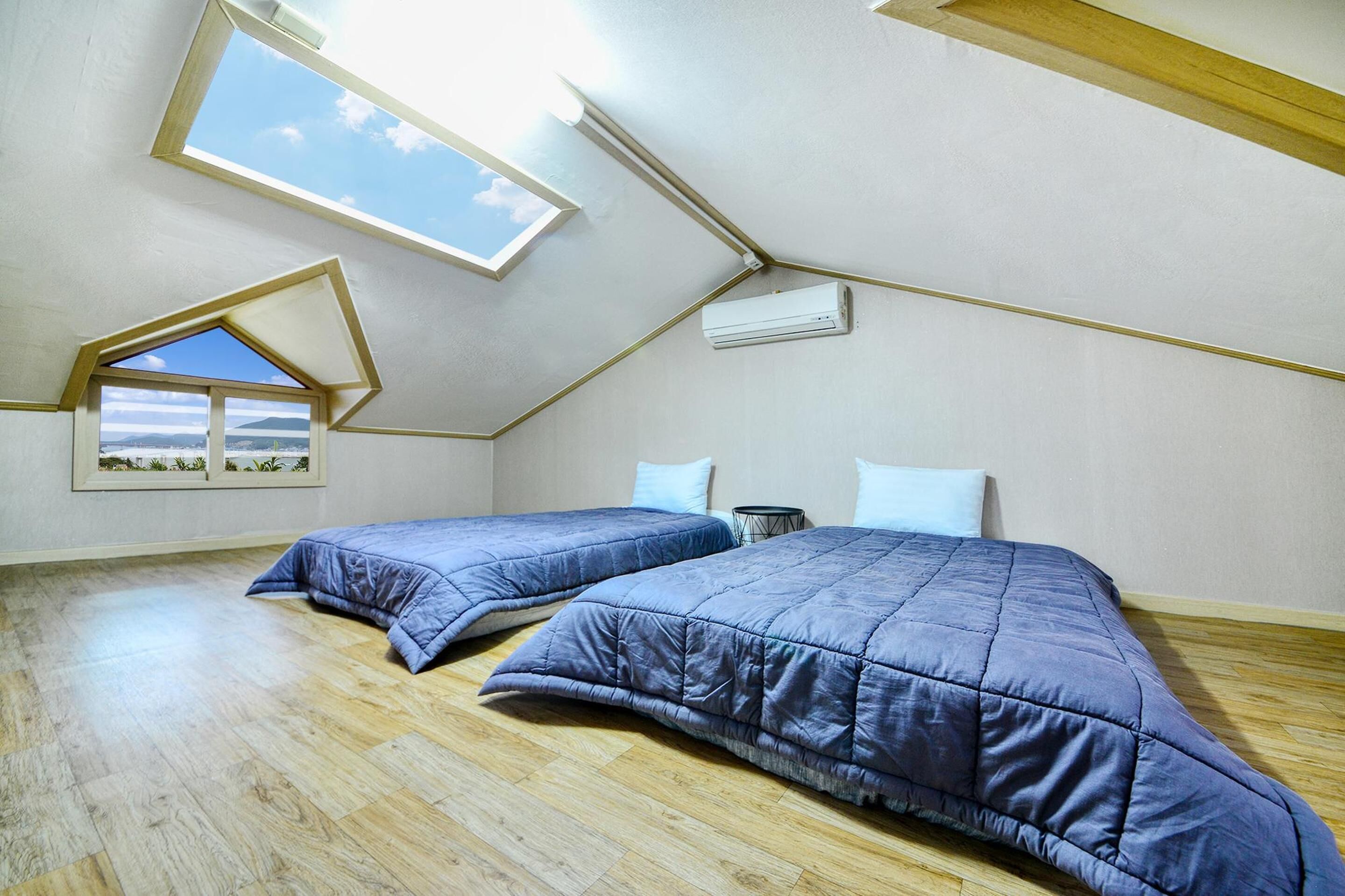 Un dormitorio con dos camas, un tragaluz y vistas a la montaña.
