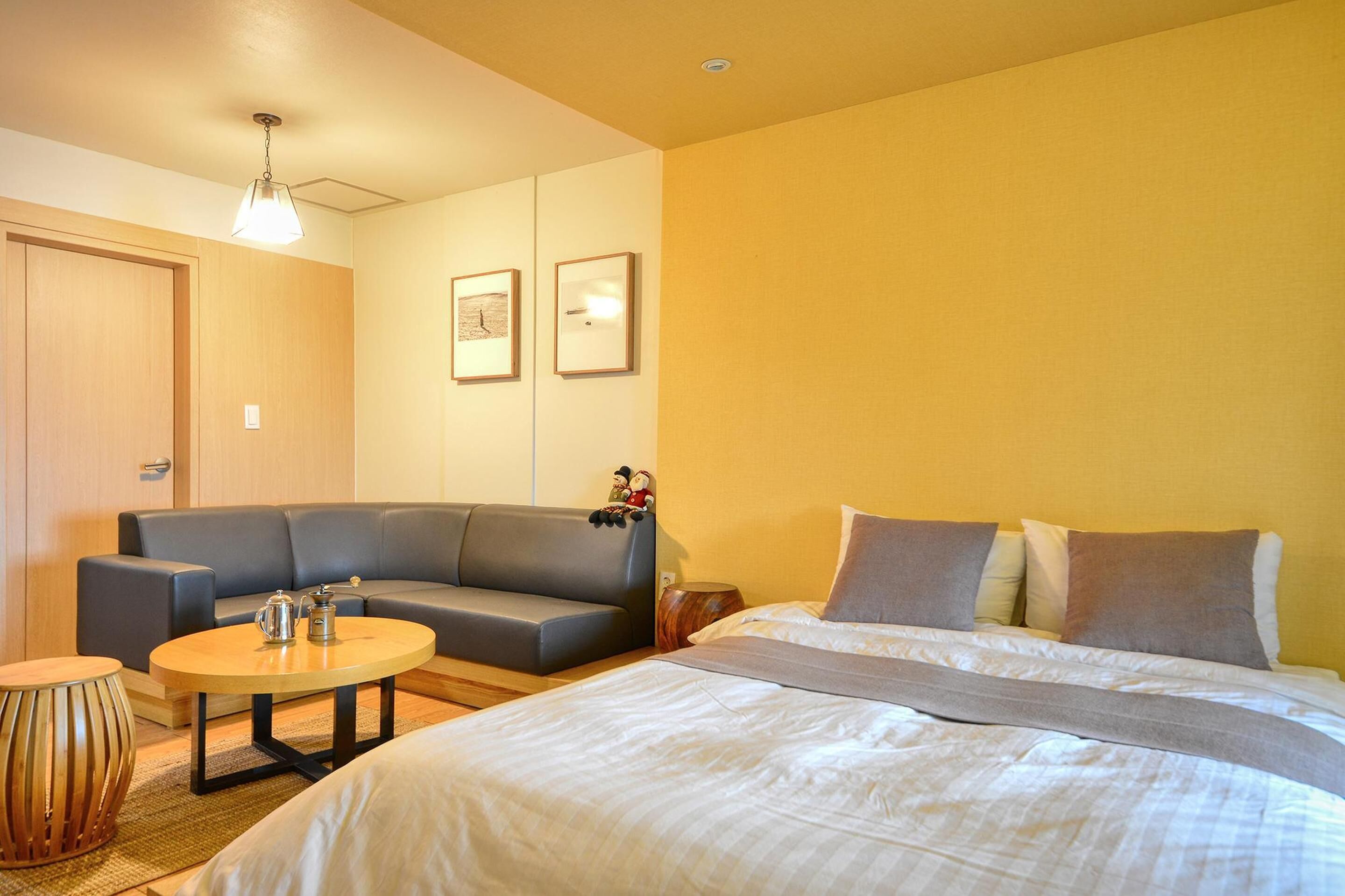 A hotel room with a bed, a sofa, a small table, and a lamp.