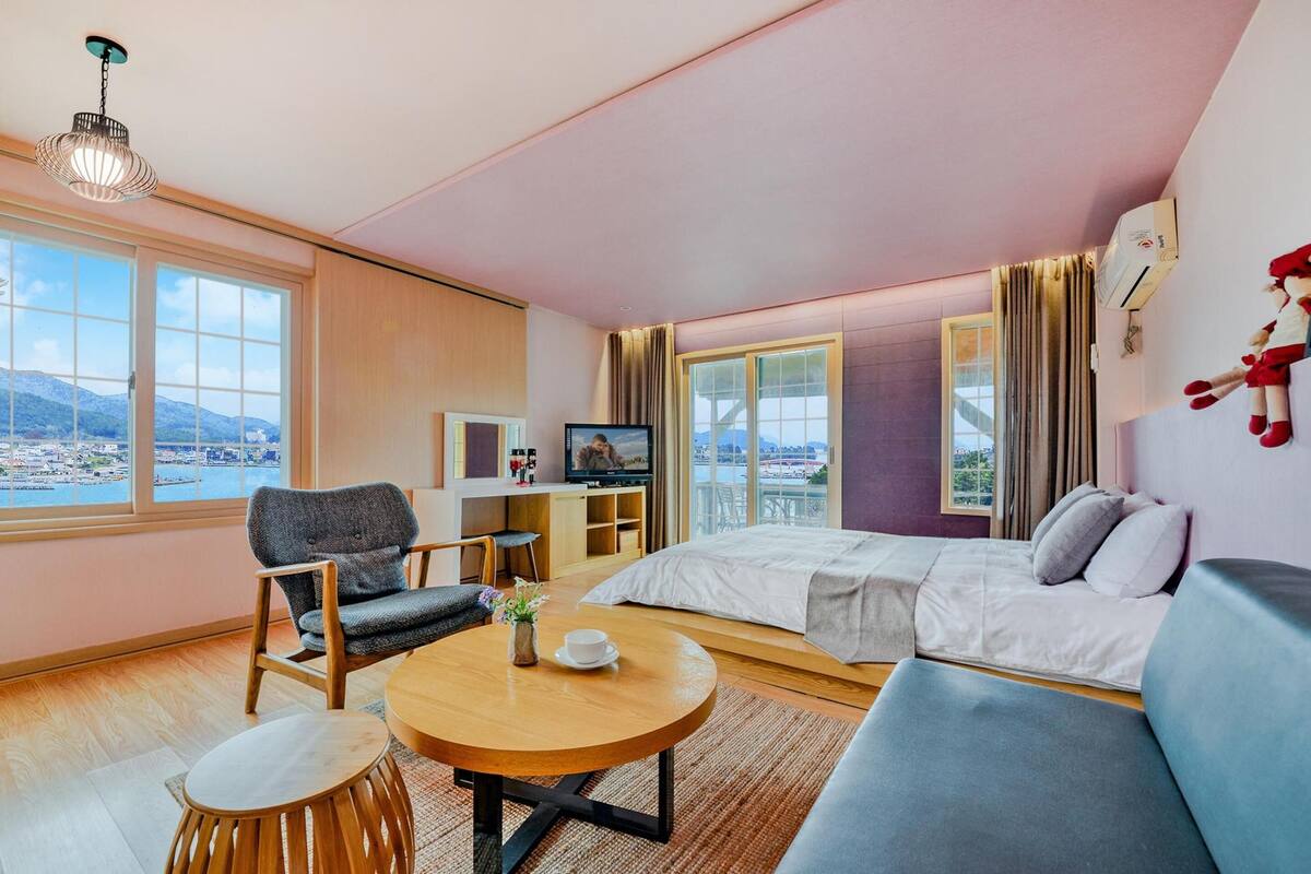 Habitación de hotel moderna con cama, sofá, escritorio y televisor.