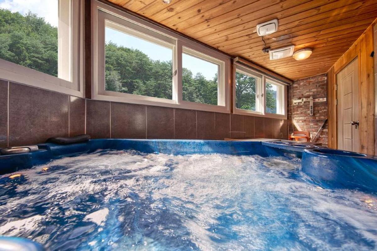 Ein Whirlpool mit Blick auf Bäume durch große Fenster.