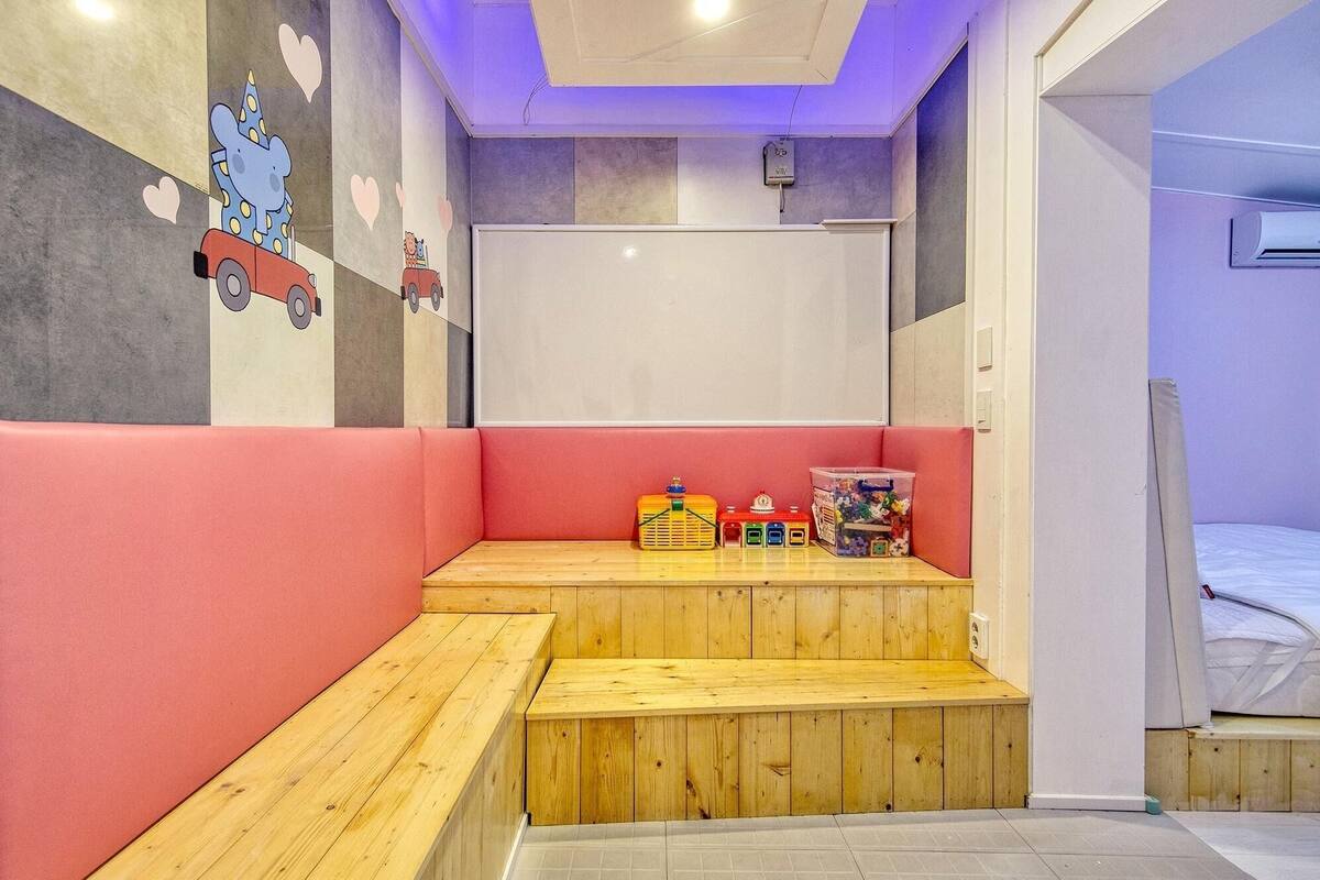Ein Zimmer mit einer hölzernen Bank, einer Tafel und einem Bett.