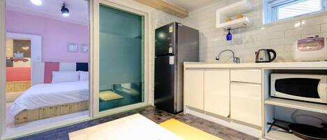 A compact kitchen with a refrigerator, microwave, and sink.