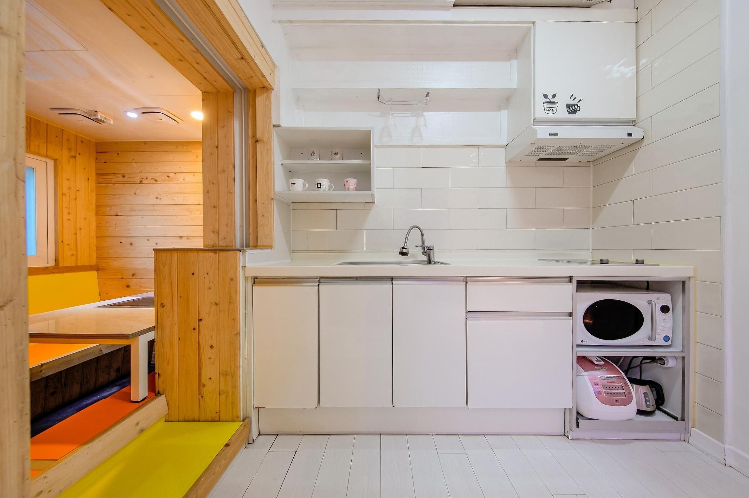 Una cocina compacta con armarios blancos, un fregadero, microondas y horno empotrado.