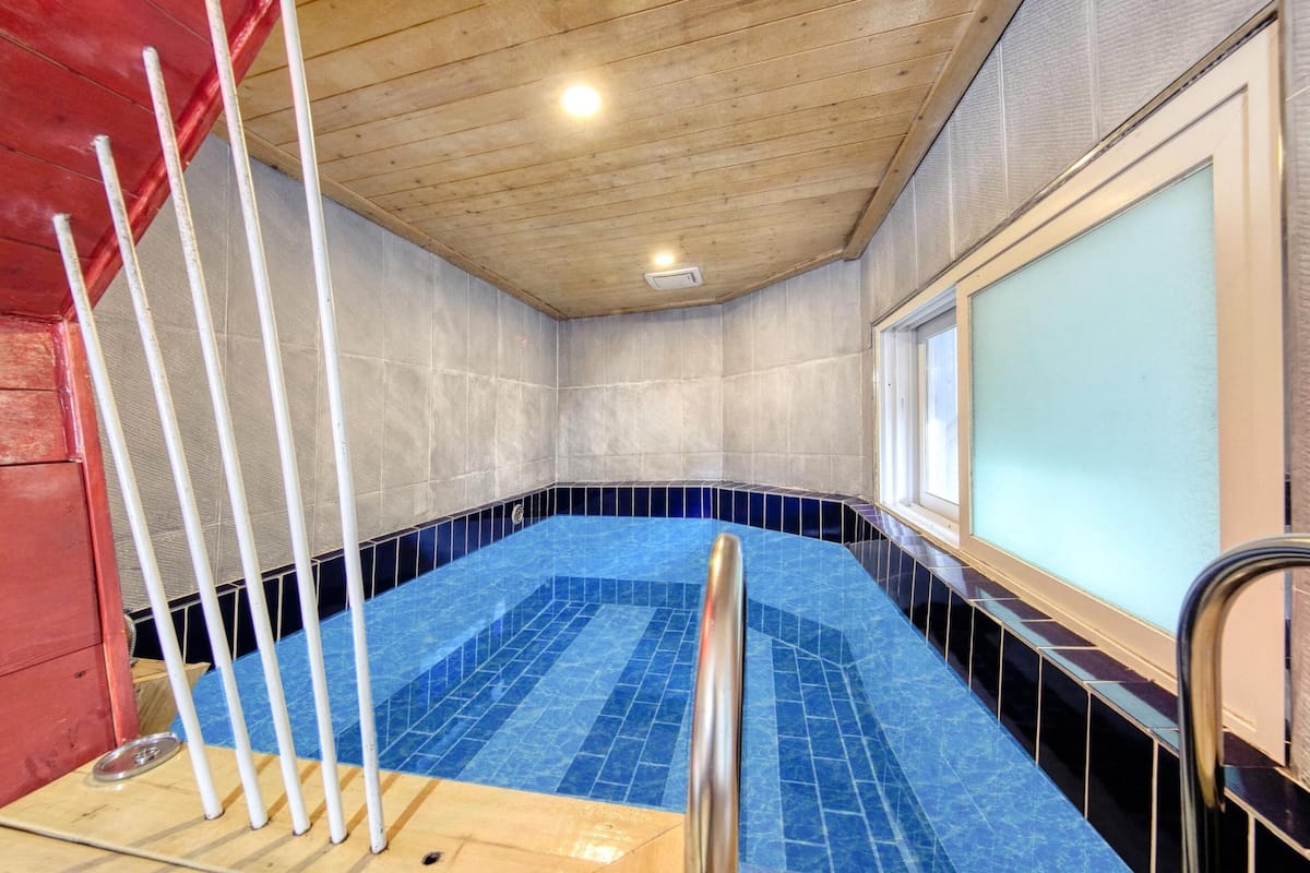 Ein Swimmingpool mit blau gefliestem Boden, umgeben von Wänden mit strukturierter Oberfläche.