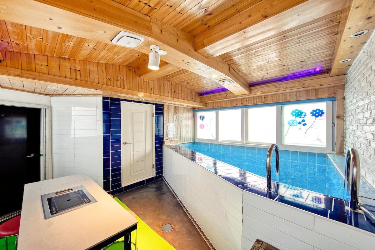 Ein Holzinnenraum mit Schwimmbecken, Tisch und Tür.