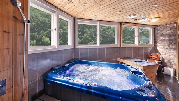 Ein Zimmer mit Holzwänden, einer großen Whirlwanne, einem Holztisch und einer Ziegelwand.