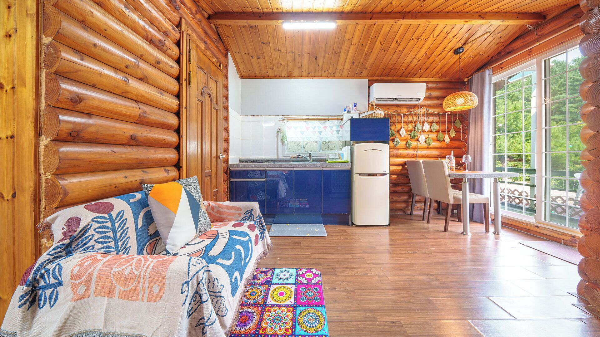 A log cabin interior with a sofa, dining table, and kitchen area.