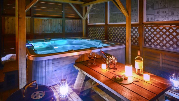 A wooden cabin with a hot tub, a table with candles, and a lantern. - Pocheon Arumdri Pension (Pocheon)