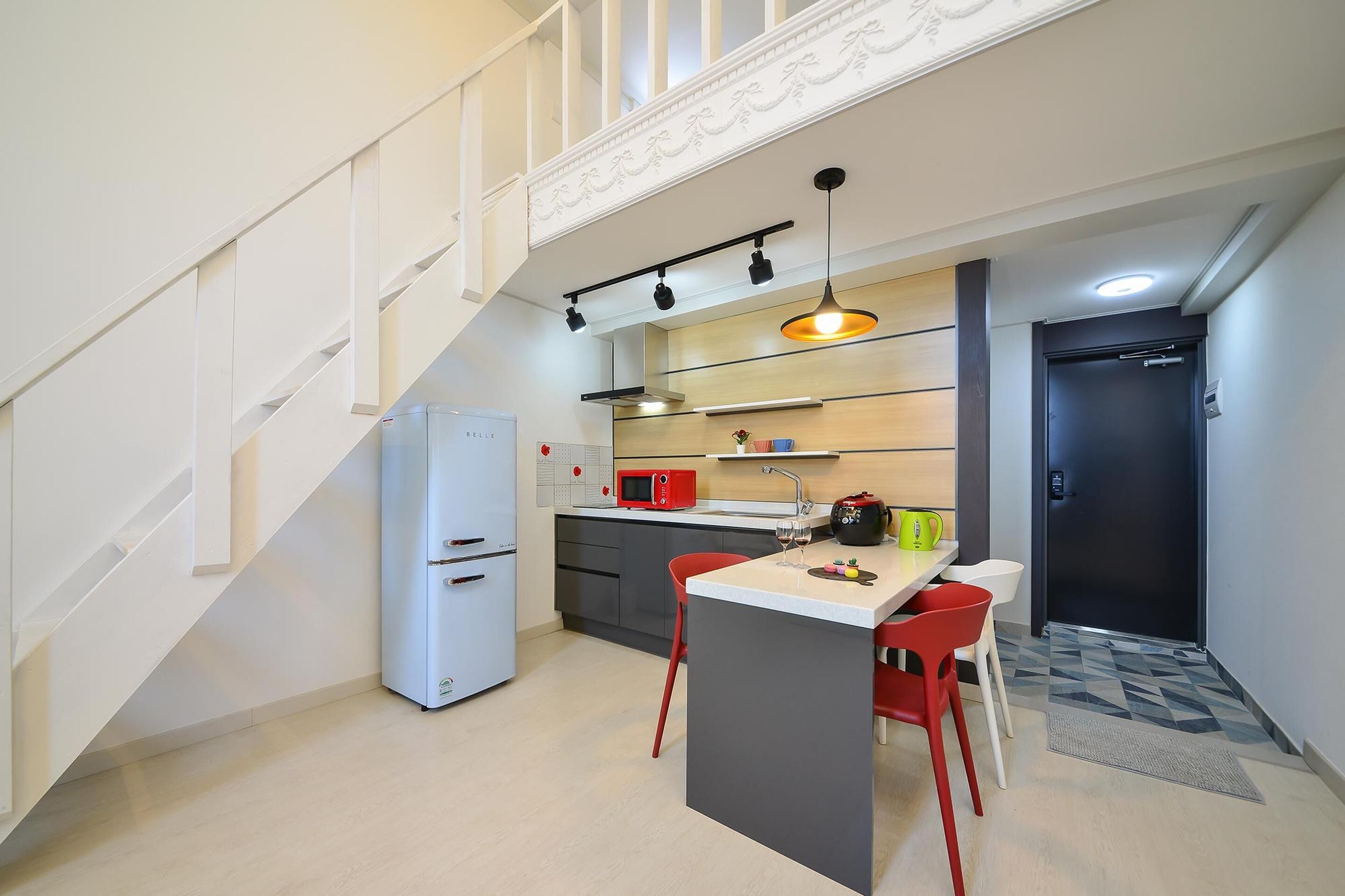 Cozinha compacta com ilha central, micro-ondas, frigorífico e pia.