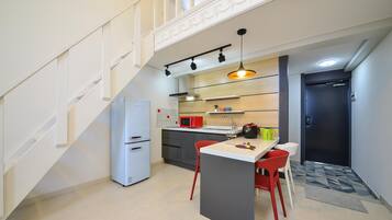 Cozinha compacta com ilha central, micro-ondas, frigorífico e pia.