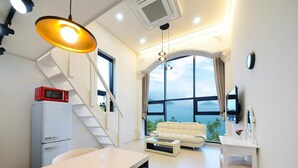 Un salon moderne avec un canapé blanc, une table à manger et une vue sur la mer.