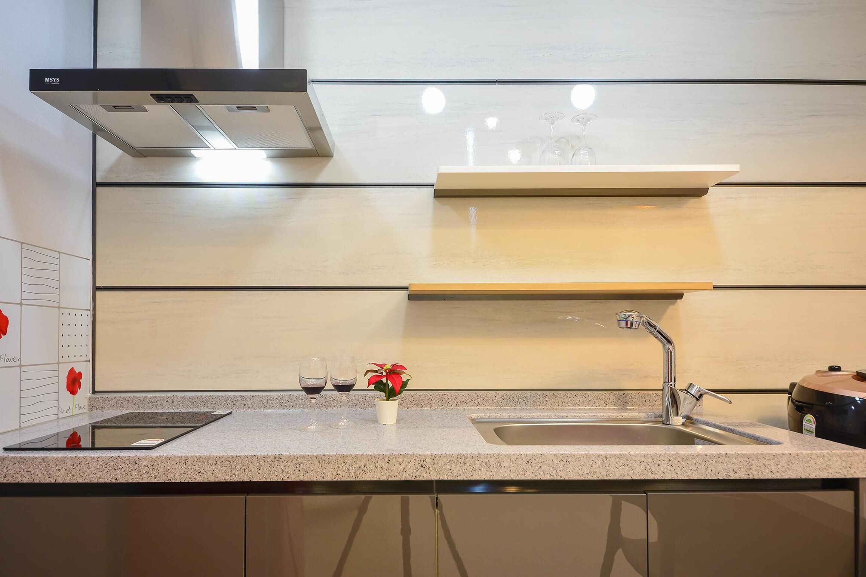 A modern kitchen with a stainless steel sink, a built-in oven, and a range hood.