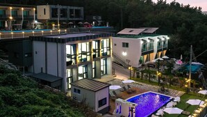 Un hôtel moderne doté d’une piscine sur le toit, d’un espace extérieur aménagé et d’une terrasse bien éclairée.