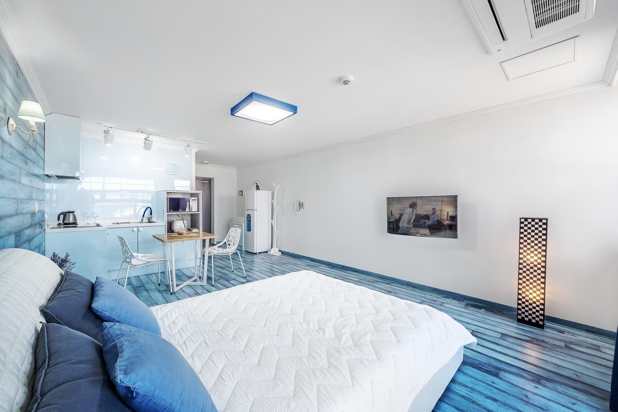 Une chambre d’hôtel moderne dotée d’un grand lit, d’une kitchenette, d’un coin repas et d’une salle de bain.