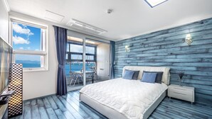 A bedroom with a large bed, a nightstand, a window with a view of a bridge, and a checkered table runner. - Geoje Healing Pension (Geoje)