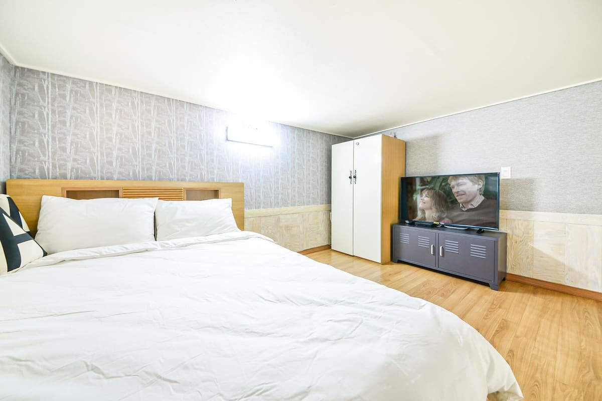 Ein Schlafzimmer mit Bett, Kleiderschrank, Fernseher und einer Wand mit Musterdesign.