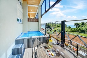A balcony with a pool, outdoor seating, and a scenic view. - Tongyoung Seychelles Poolvilla (Tongyeong)