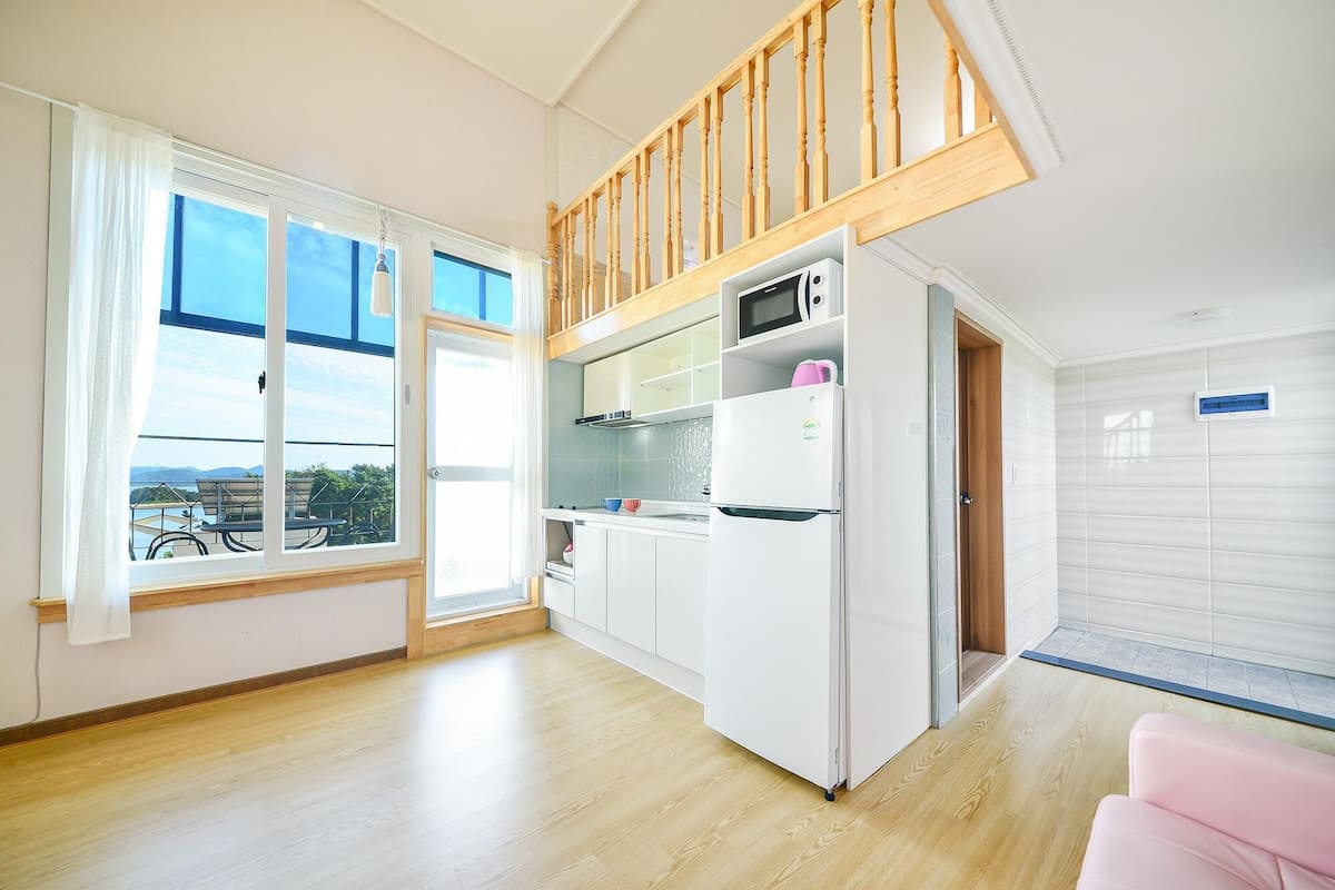 Eine moderne Küche mit integriertem Mikrowellenherd, einem Kühlschrank und einer Holzbalkendecke.
