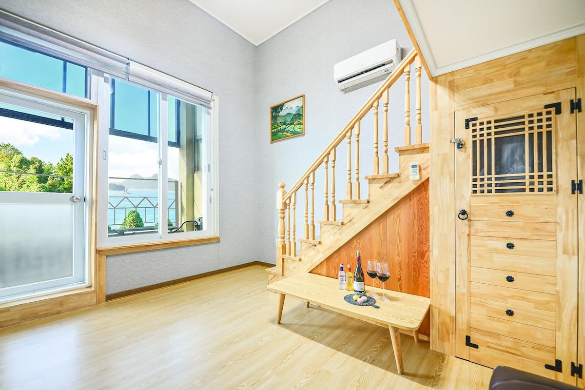 Ein Zimmer mit einer Holztreppe, einem Holzschrank und einem Tisch mit Flaschen und Gläsern.