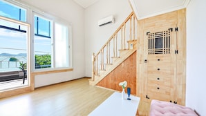 A modern room with a wooden staircase, a white table with a vase, and a view of the outdoors. - Tongyoung Seychelles Poolvilla (Tongyeong)