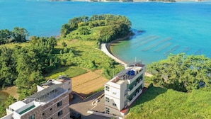 A coastal area with buildings, a clear blue sea, and green vegetation. - Tongyoung Seychelles Poolvilla (Tongyeong)