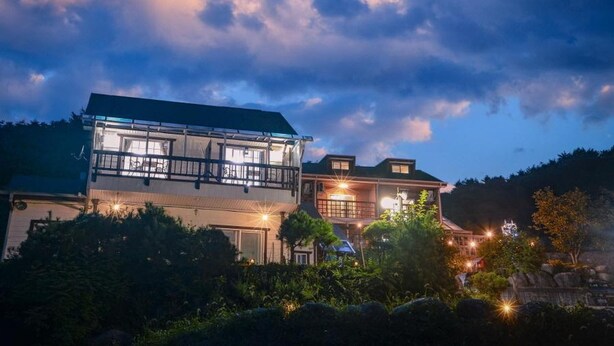 A two-story building with a balcony and multiple windows, surrounded by greenery. - Yangyang Water Sol Valley Pension (Yangyang)