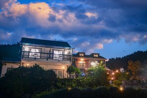 A two-story building with a balcony and multiple windows, surrounded by greenery. - Yangyang Water Sol Valley Pension (Yangyang)
