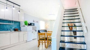A modern kitchen with white cabinets, a blue backsplash, and a dining area with wooden chairs. - Yangyang Water Sol Valley Pension (Yangyang)
