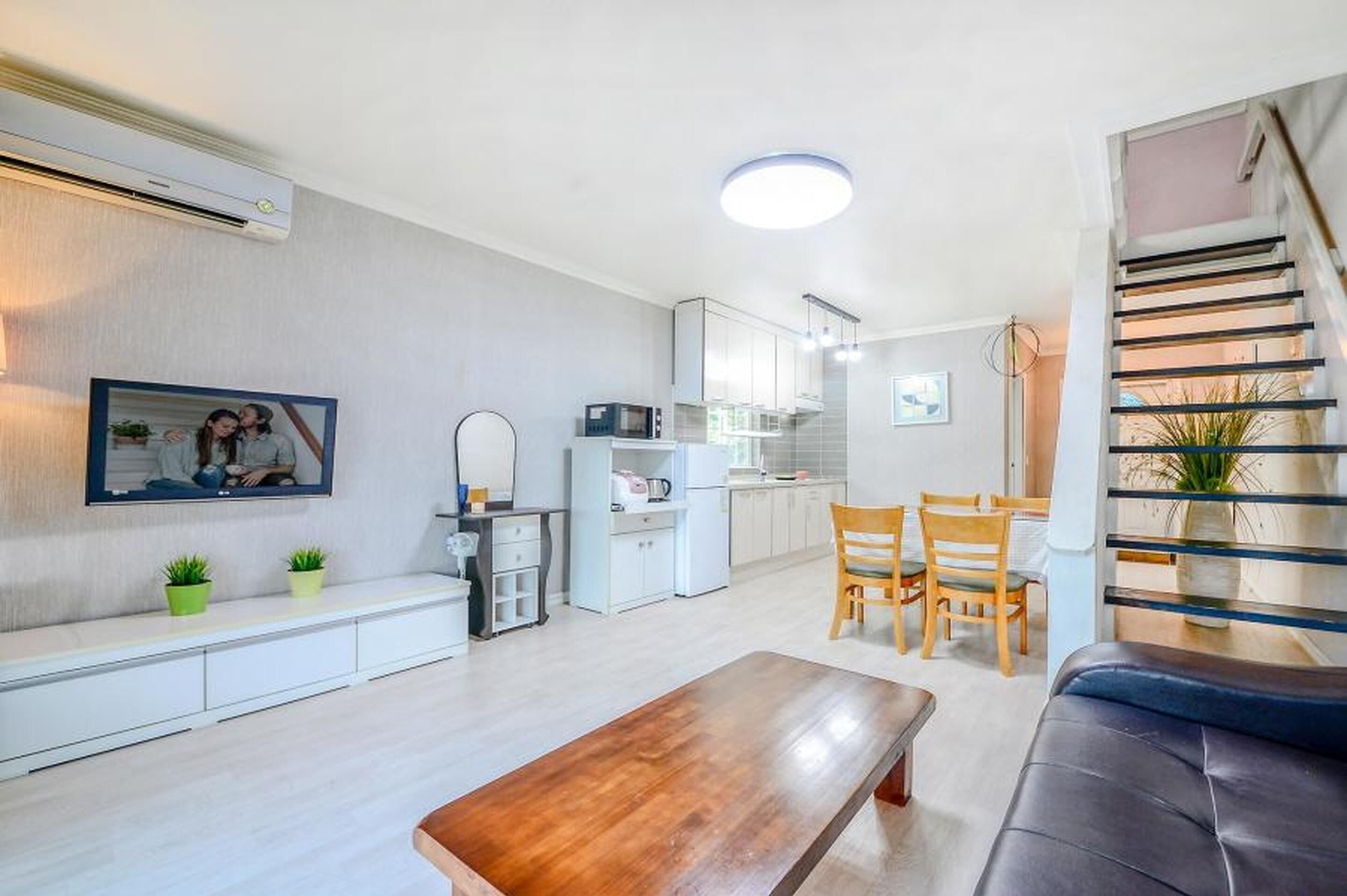 Een moderne woonruimte met keuken, eethoek en trap.