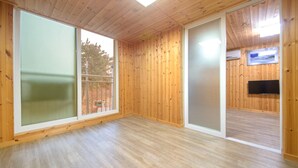 A room with wooden walls and floors, large windows, and a flat-screen TV mounted on the wall. - Samcheok sky Pension (Samcheok)